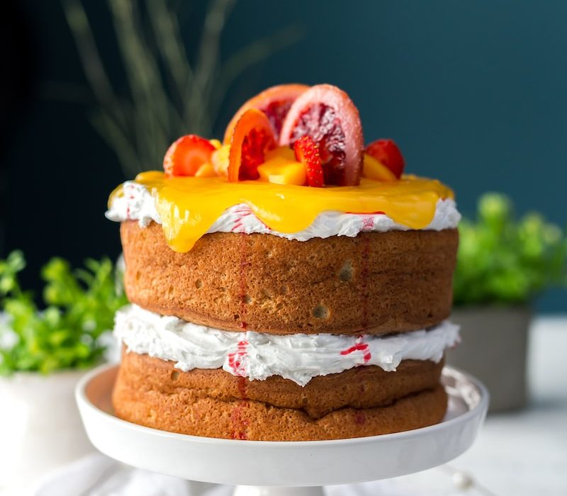 two-layered cake with citrus fruit and strawberry toppings